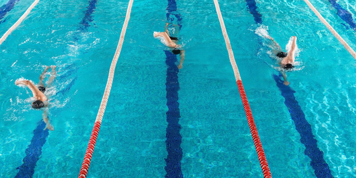 Three male swimmers racing against each other in a swiming pool